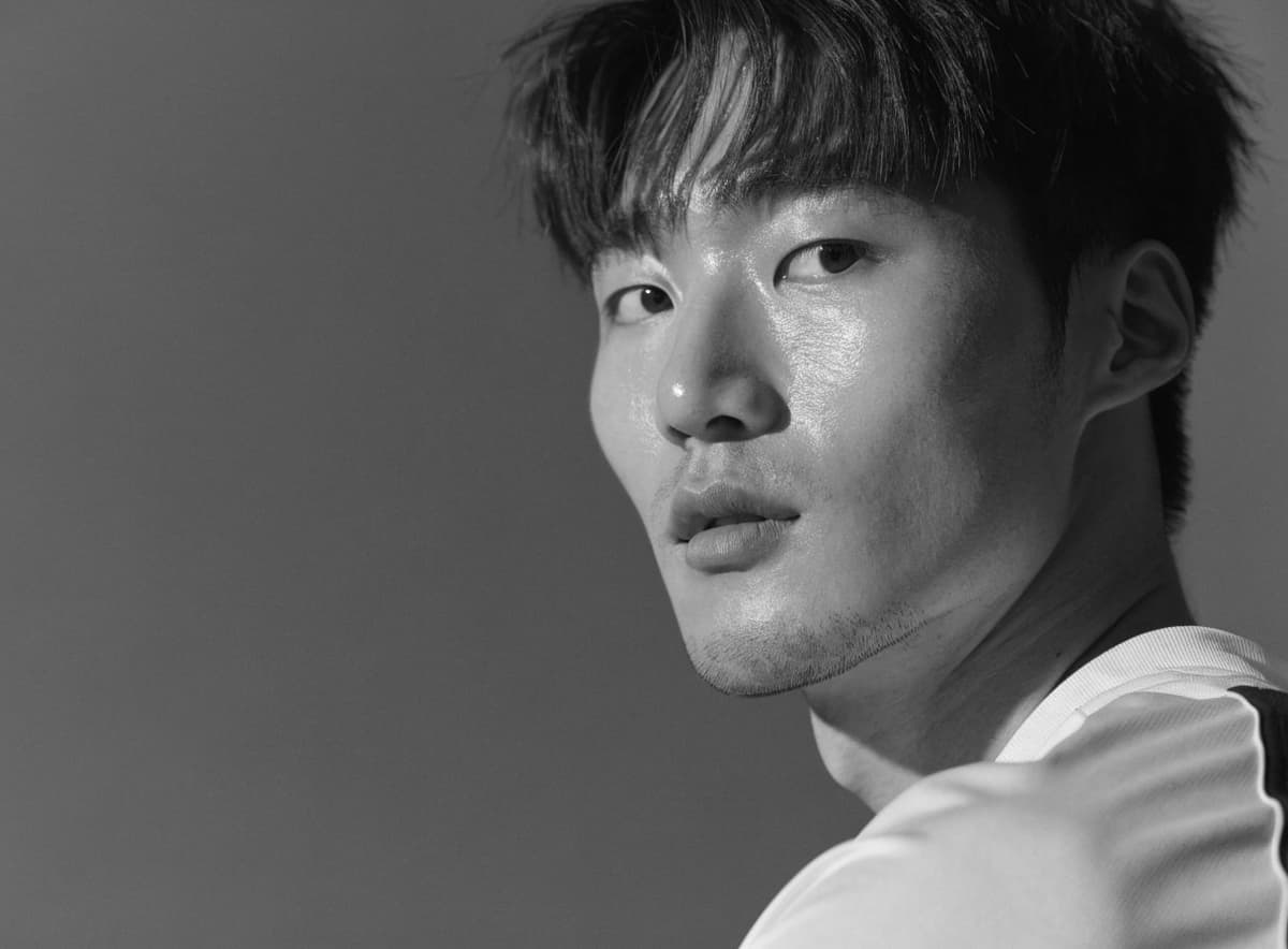 A Korean football player in a white and navy shirt